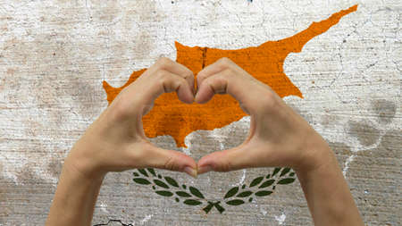 With a stylized Cypriot flag background an anonymous person's hands being held in the form of a heart, symbolizing love and patriotism for Cyprus.の写真素材