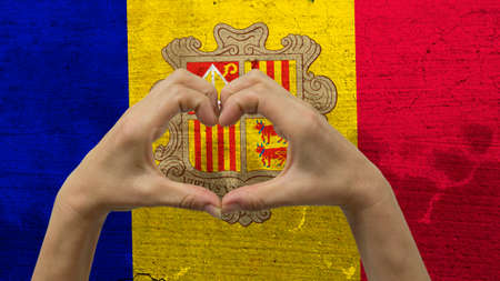 With a stylized Andorran flag background an anonymous person's hands being held in the form of a heart, symbolizing love and patriotism for Andorra.の写真素材