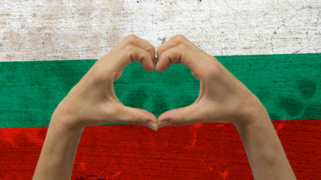 With a stylized Bulgarian flag background an anonymous person's hands being held in the form of a heart, symbolizing love and patriotism for Bulgaria.の写真素材