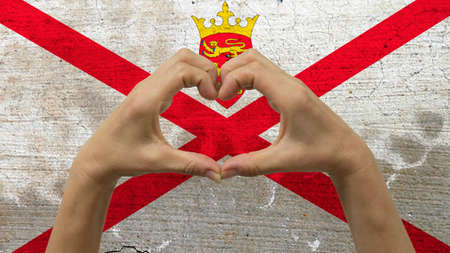 With a stylized Jersey flag background an anonymous person's hands being held in the form of a heart, symbolizing love and patriotism for Jerseyの写真素材