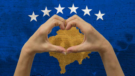 With a stylized Kosovan flag background an anonymous person's hands being held in the form of a heart, symbolizing love and patriotism for Kosovo.の写真素材