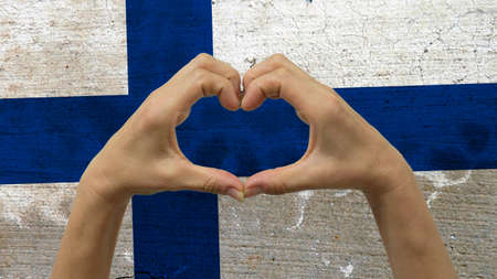 With a stylized Finnish flag background an anonymous person's hands being held in the form of a heart, symbolizing love and patriotism for Finland.の写真素材