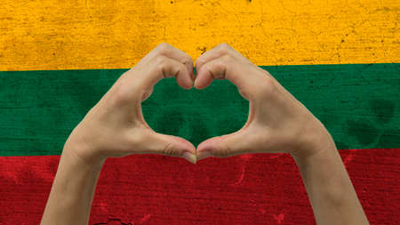 With a stylized Lithuanian flag background an anonymous person's hands being held in the form of a heart, symbolizing love and patriotism for Lithuania.の写真素材