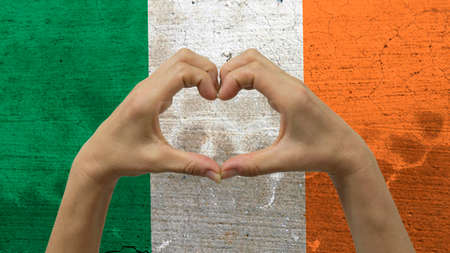 With a stylized Irish flag background an anonymous person's hands being held in the form of a heart, symbolizing love and patriotism for Ireland.の写真素材