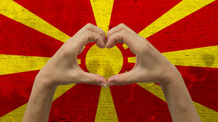 With a stylized Macedonia flag background an anonymous person's hands being held in the form of a heart, symbolizing love and patriotism for Macedonia.の写真素材