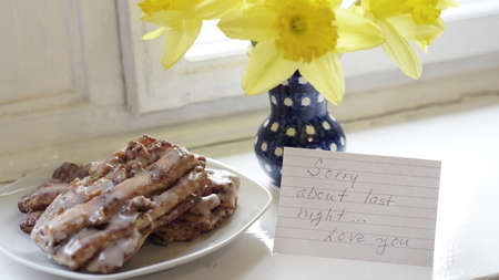 A note with the message Sorry About Last Night with a bunch of flowers and some baked pastries.の写真素材