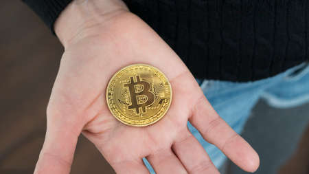 Close up shot of a woman with a Bitcoin cryptocurrency coin in her open hand.の写真素材