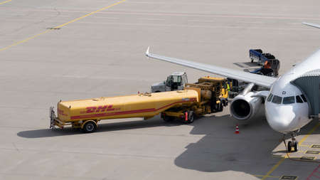 SCHKEUDITZ, GERMANY - AUG 15, 2018: A DHL fuel tanker delivery truck loads jet fuel onto a passenger jet airplane at the Halle - Leipzig airport in Germanyのeditorial素材