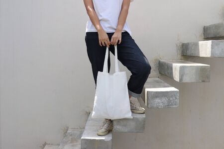 model hold blank white fabric tote bag for save environment on street fashion with white t-shirtの写真素材