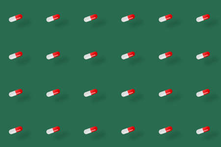 Colorful pattern of pills on green background with shadows. Seamless pattern with capsules. Medical, pharmacy and healthcare conceptの写真素材