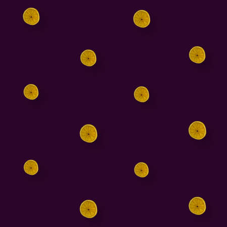 Colorful pattern of dried orange slices on dark violet background. Dried orange chips. Top view. Flat lay. Pop artの写真素材
