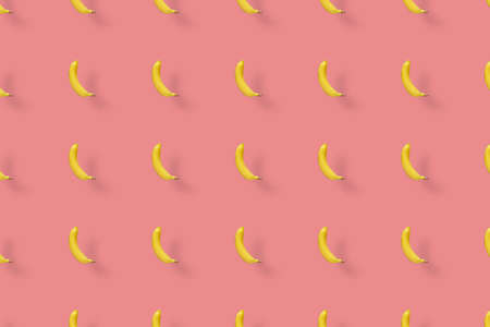 Colorful fruit pattern of yellow bananas on pink background. Top view. Flat lay. Pop art designの写真素材