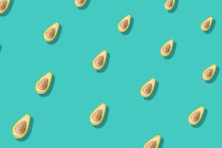 Colorful pattern of fresh avocados on turquoise background with shadows. Top view. Flat lay. Pop art designの写真素材