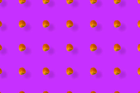 Colorful fruit pattern of fresh persimmons on purple background. Top view. Flat lay. Pop art designの写真素材
