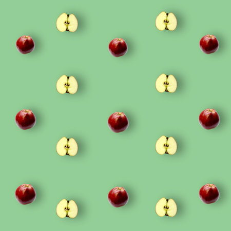 Colorful fruit pattern of fresh red apples sliced on green background. Top view. Flat lay. Pop art design, creative summer conceptの写真素材