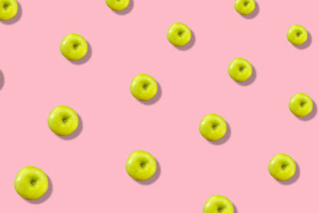 Colorful fruit pattern of fresh green apples on pink background with shadow. Top view. Flat lay. Pop art design, creative summer conceptの写真素材