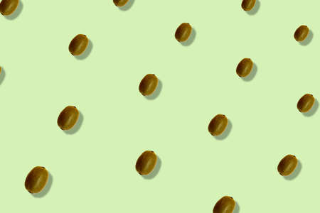 Colorful fruit pattern of fresh kiwi on light green background with shadows. Top view. Flat lay. Pop art designの写真素材