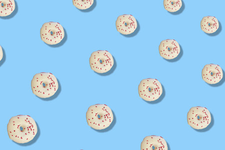 Colorful pattern of white glazed donuts isolated on blue background with shadows. Doughnuts. Top view. Flat layの写真素材
