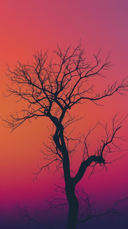 Silhouette of a bare tree against a vibrant sunsetの素材