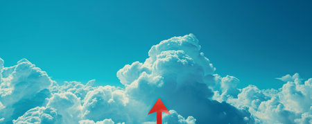 Fluffy white cumulus clouds in a clear blue sky with a red arrow pointing upward. Weather and navigation conceptの素材