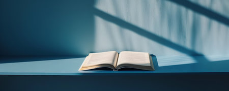 Open book on a blue surface with shadows cast on the wallの素材