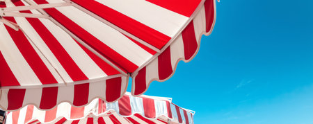 Red and white striped umbrellas with clear blue sky, summer vacation conceptの素材
