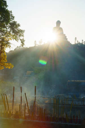 Giant Buddha in forest on sunset with sun lightの写真素材