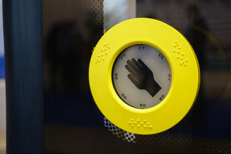Yellow bus button with hand on side of busの写真素材