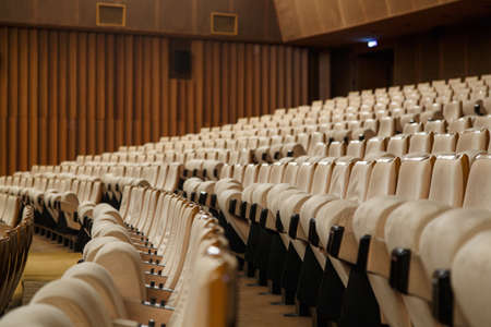 Empty cinema hall with a lot of beige armchairs, dim lightの写真素材