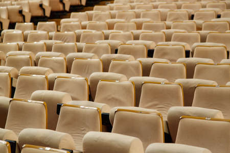 Empty cinema hall with a lot of beige armchairs, dim lightの写真素材