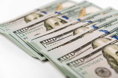 Heap of hundred dollar banknotes on a white surfaceの写真素材