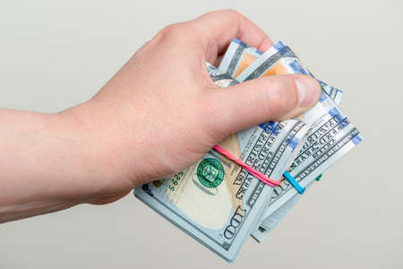 Male hand holding packs of one hundred dollar banknotesの写真素材