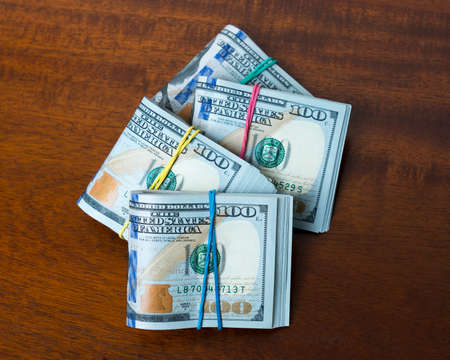 Piles of hundred dollar bills on wooden table