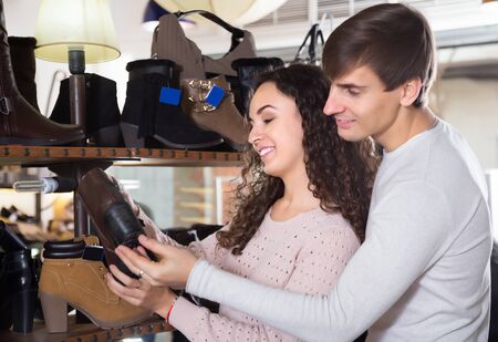 Smiling young man and woman buying winter shoes in a shoe storeの写真素材