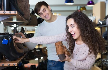 Happy young couple buying winter shoes in a shoe shopの写真素材