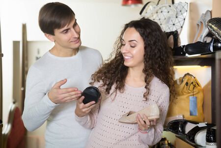Smiling girl with a guy choosing summer women shoes in a shoe storeの写真素材