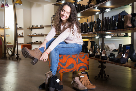Smiling female choosing winter women shoes in a shoe shopの写真素材