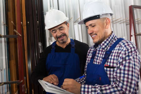 Satisfied manager discussing job with worker at windows factoryの写真素材