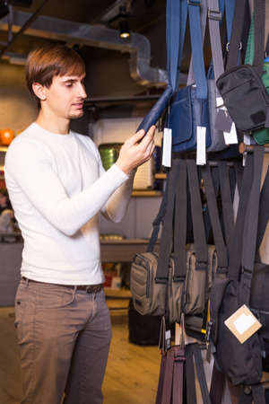 Young man buying new textile purse in haberdashery storeの写真素材