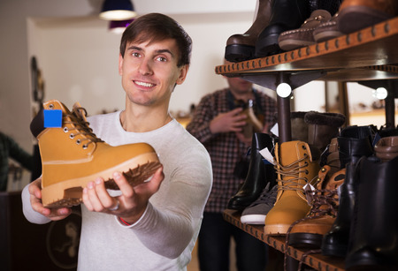 Positive man with the shoe in his handsの写真素材