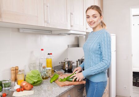 Smiling young householder learning new recipe of vegetables at homeの写真素材