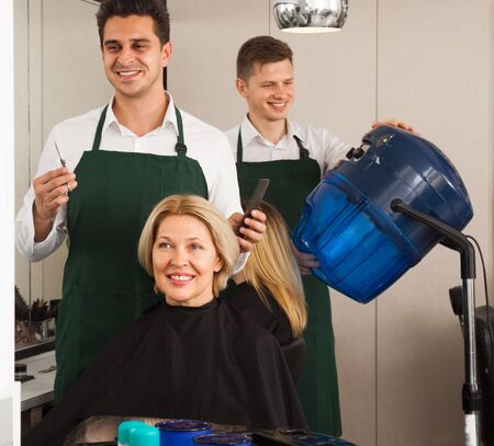 stylist cutting hair of elderly blonde Woman hairdresser in salonの写真素材