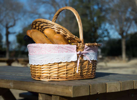 picnic basket with bread and wine on table in parkの写真素材