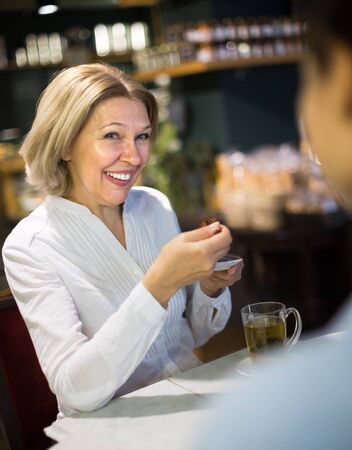 mature woman drinking tea and talking in coffee-houseの写真素材
