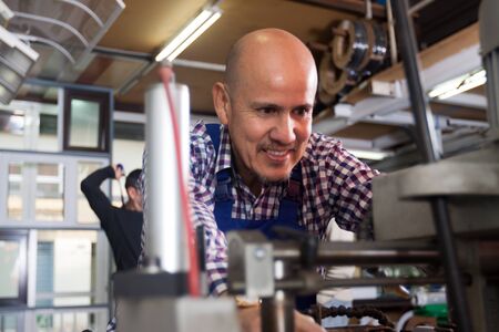 Portrait of debonair middle age worker at professional lathe in plantの写真素材
