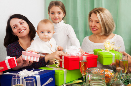 Men and women around festive table with gifts at homeの写真素材