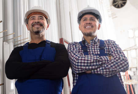 Happy professional workers in in helmet and uniform at modern industry plantの写真素材