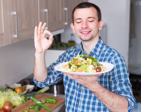 young guy posing with a plate of saladの写真素材