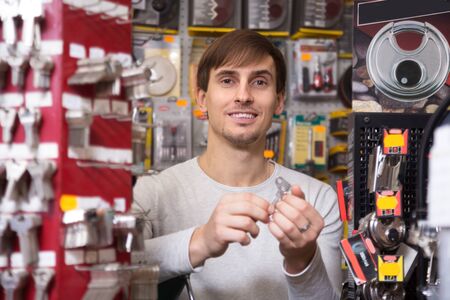 Happy young ordinary handyman making copies of door keys  in locksmithの写真素材
