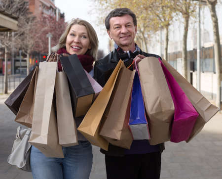 Portrait of smiling senior couple with shopping bags outdoors